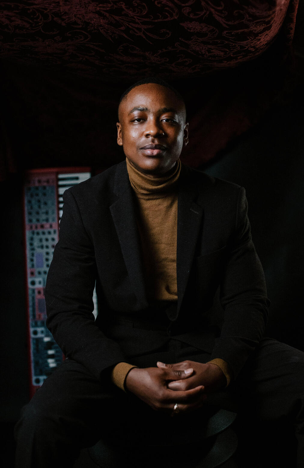 Allen Ukah, composer, photographed by Meanz Chan in front of a Nord keyboard.